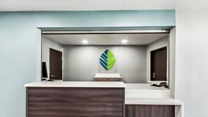 Un baño moderno con un espejo grande, un tocador de madera y una decoración en forma de hoja verde en la pared.