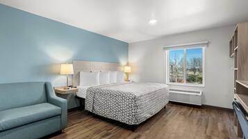 Una habitación de hotel moderna con cama, sofá, mesita de noche, lámpara y ventana con vistas.