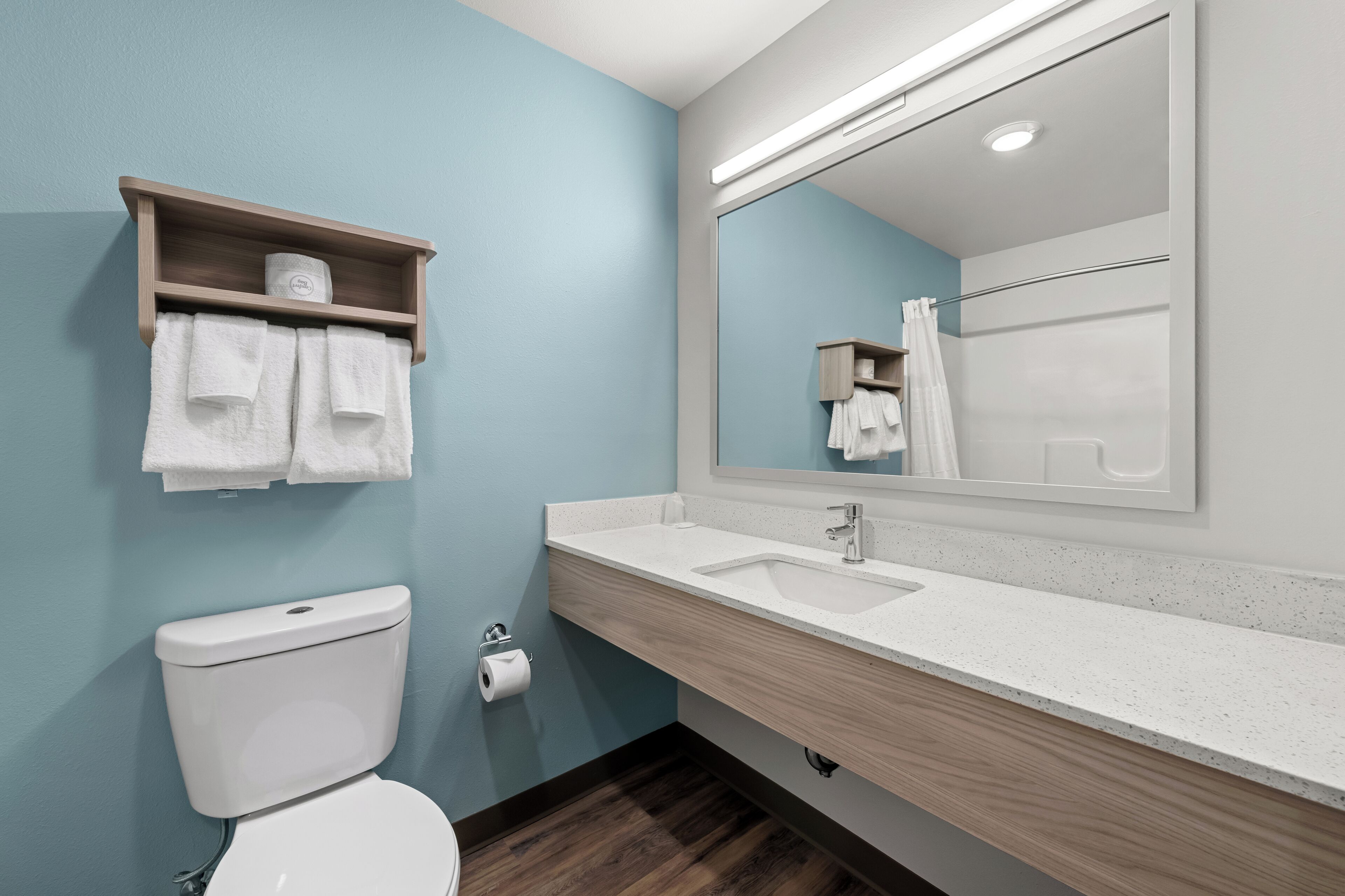 A modern bathroom with a toilet, sink, and mirror.