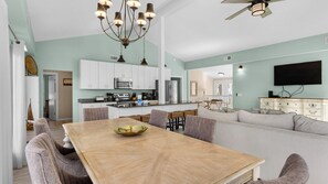 A modern kitchen with white cabinets, stainless steel appliances, and a dining area with a wooden table and chairs. - Your Ideal Beach Getaway With Private Pool, Game Room and Close to Beach! (Santa Rosa Beach)
