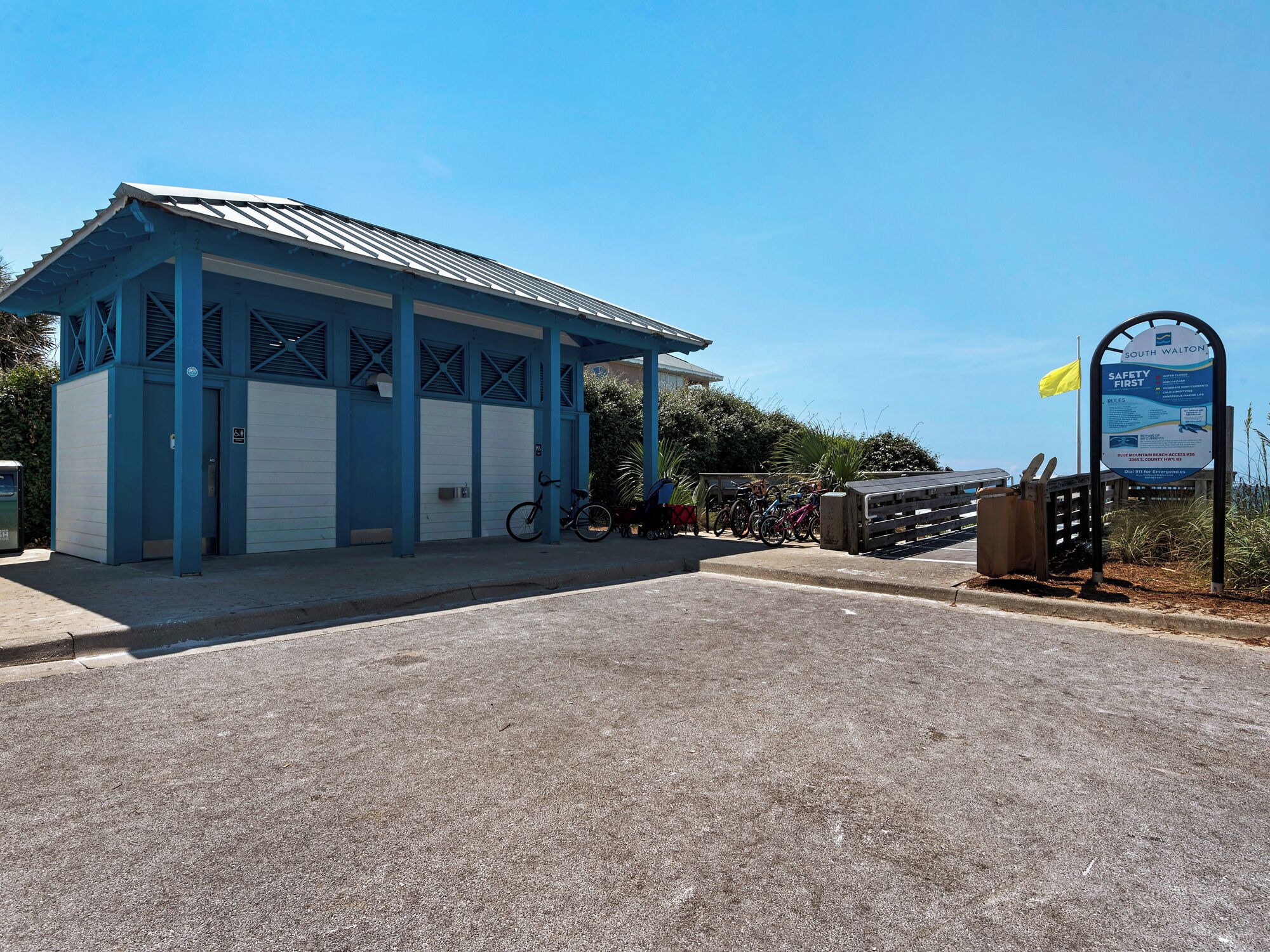 A blue building with a covered entrance, a signboard, and bicycles parked outside.