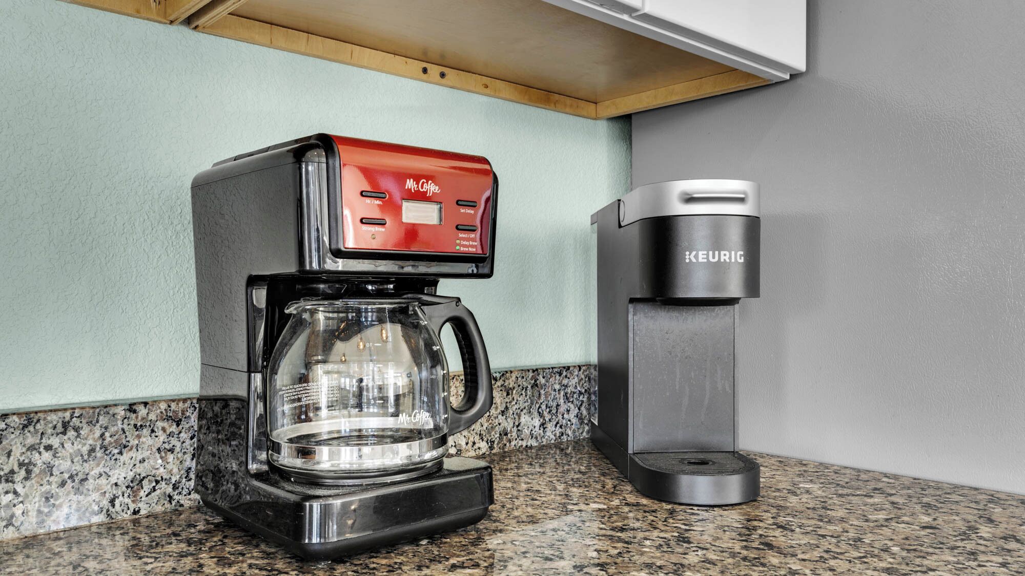 Eine Keurig-Kaffeemaschine mit Glasbehälter auf einer Granit-Arbeitsplatte.