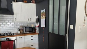 A modern kitchen with white cabinets, a wooden countertop, a microwave, and a black door. - Charming house with pool and garden, 10 minutes from the sea (Biscarrosse)