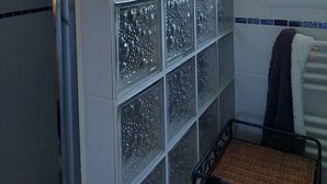 A bathroom with frosted glass windows, a towel rack, and a wicker chair. - Charming house with pool and garden, 10 minutes from the sea (Biscarrosse)