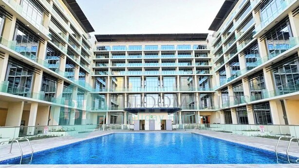 A modern building with a central swimming pool, multiple balconies, and large windows. - Bloomfields Executive 1BR Oasis Masdar (Abu Dhabi)