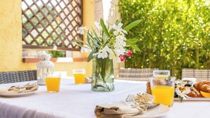 Une table de petit-déjeuner avec des assiettes remplies de nourriture, des verres de jus d’orange et un vase de fleurs.