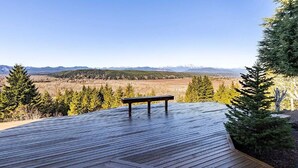 Une terrasse en bois avec un banc donnant sur un paysage montagneux.
