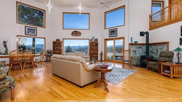 Un salon spacieux avec un grand canapé, un parquet en bois et de nombreuses fenêtres offrant une vue panoramique.