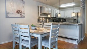 A modern kitchen with white cabinetry, a central island, and pendant lighting. - The Last Frontier Lake House Lodge in Anchorage 3bdrm 2ba (Anchorage)