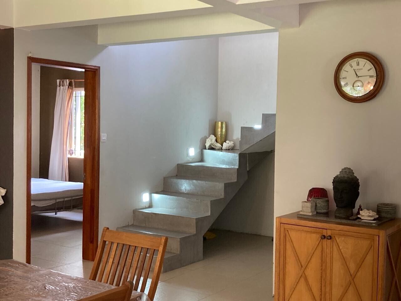Un escalier menant à une chambre à coucher où l’on aperçoit le lit à travers une porte entrouverte.