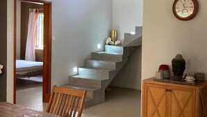 Una escalera que lleva a un dormitorio, donde se ve una cama a través de una puerta abierta.
