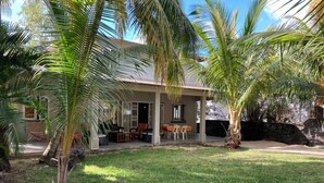Una casa con un porche cubierto, mobiliario exterior y palmeras.