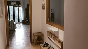 En gang med flisegulv, en træbænk, et lille bord og en pendel.