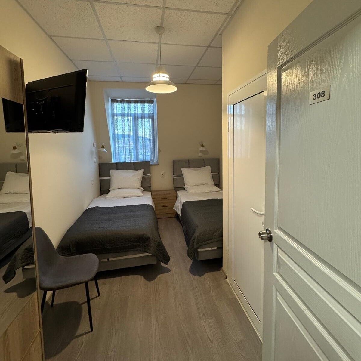 Een hotelkamer met twee bedden, een televisie, een bureau en een stoel.