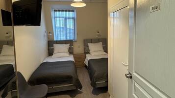 Een hotelkamer met twee bedden, een televisie, een bureau en een stoel.