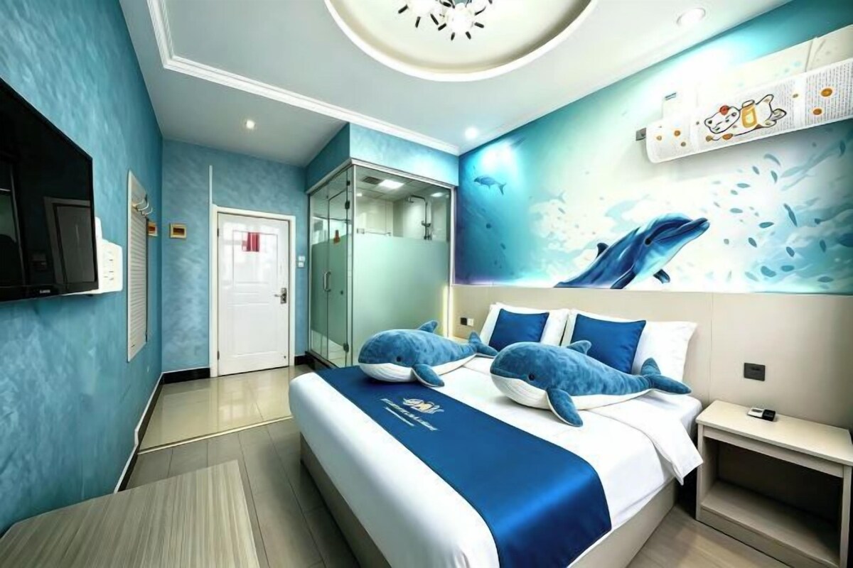Une chambre d’hôtel moderne équipée d’un grand lit, d’une télévision, d’une armoire et d’une salle de bain.