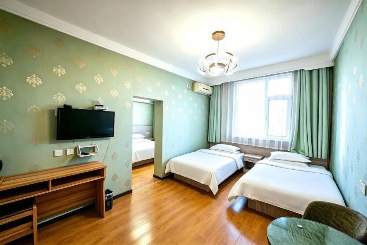 Une chambre d’hôtel avec deux lits, une télévision, un bureau et une chaise.