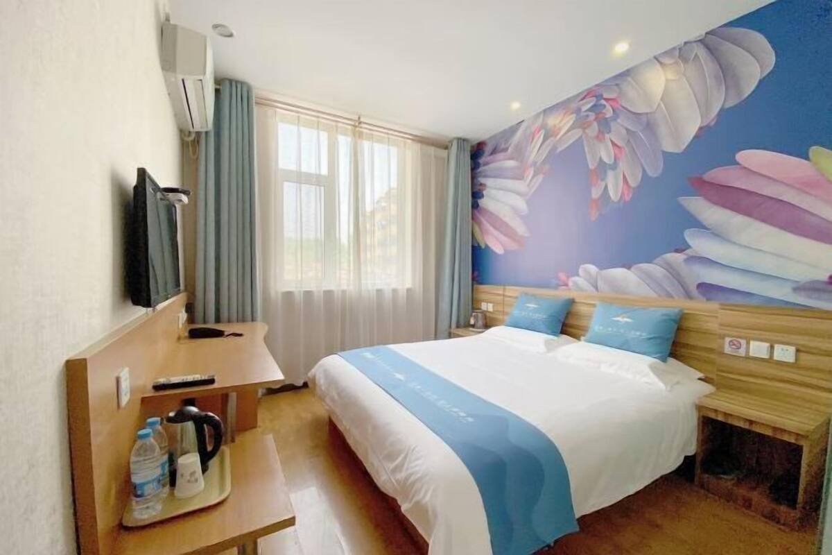 Een hotelkamer met een bed, een bureau met een waterkoker, een waterfles en een koffiezetapparaat.
