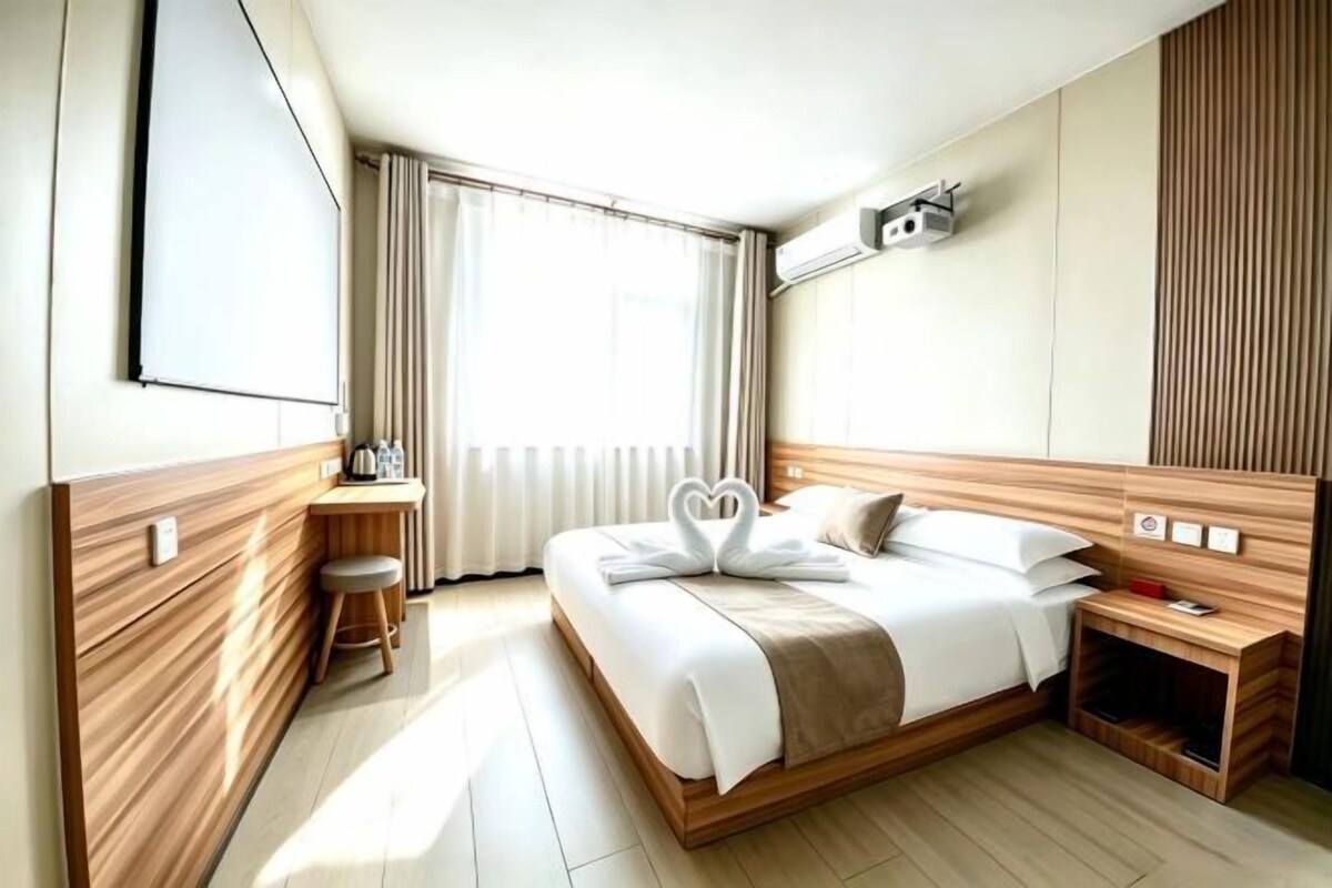 Une chambre d’hôtel comprenant un lit, une table de chevet et un bureau avec une chaise.