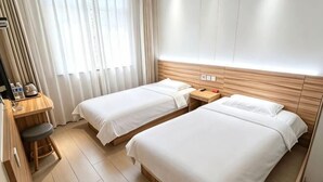 Habitación de hotel con dos camas, un escritorio con silla, una mesita y una ventana con cortinas.