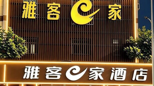 Entrada de hotel con un cartel llamativo que presenta una 'C' estilizada y caracteres chinos.
