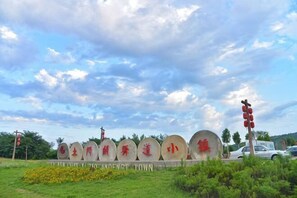 Une série de structures circulaires en pierre, ornées d’inscriptions, un panneau de signalisation routière et un véhicule, le tout dans un espace aménagé.