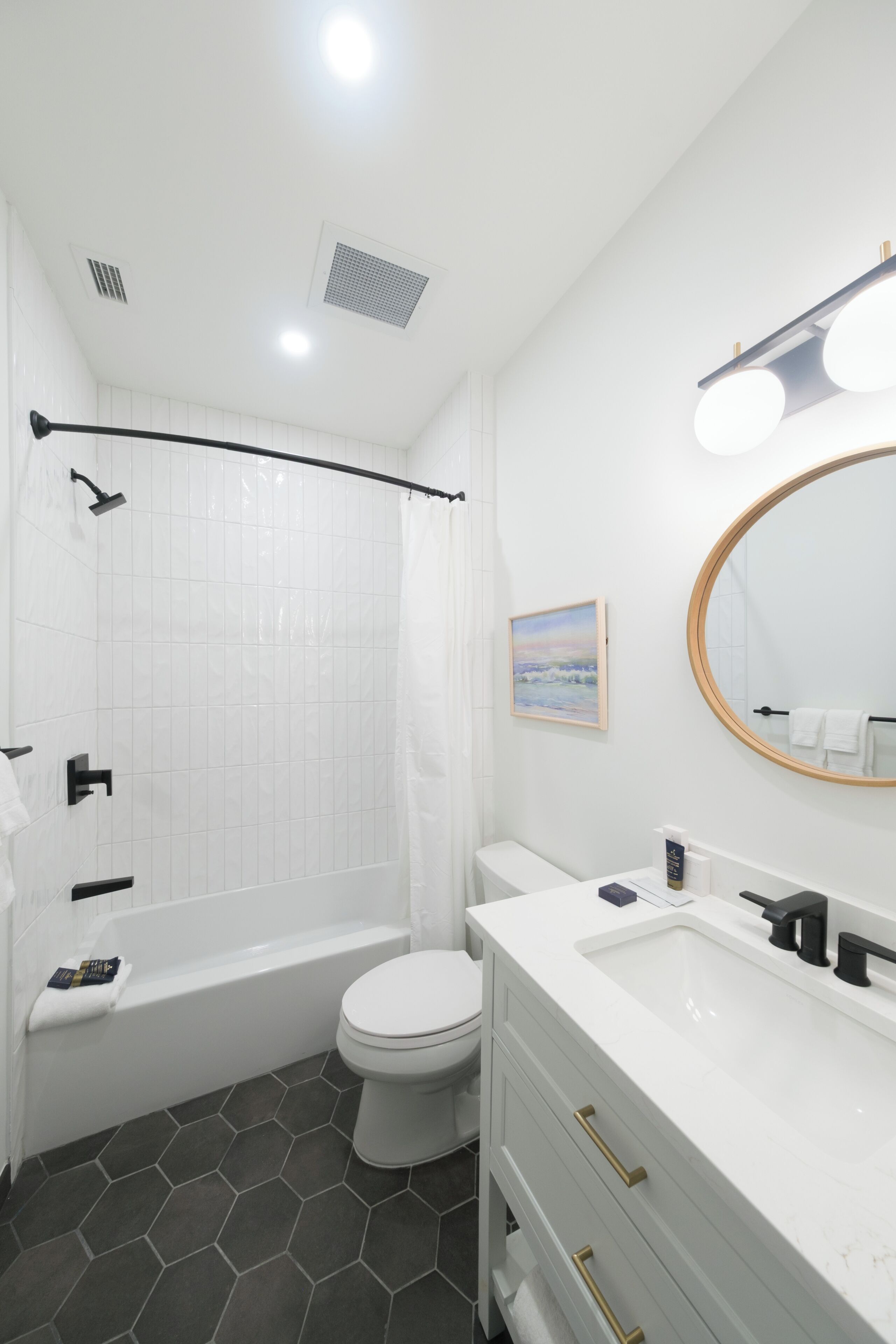 A modern bathroom with a shower, toilet, vanity, and a large mirror.