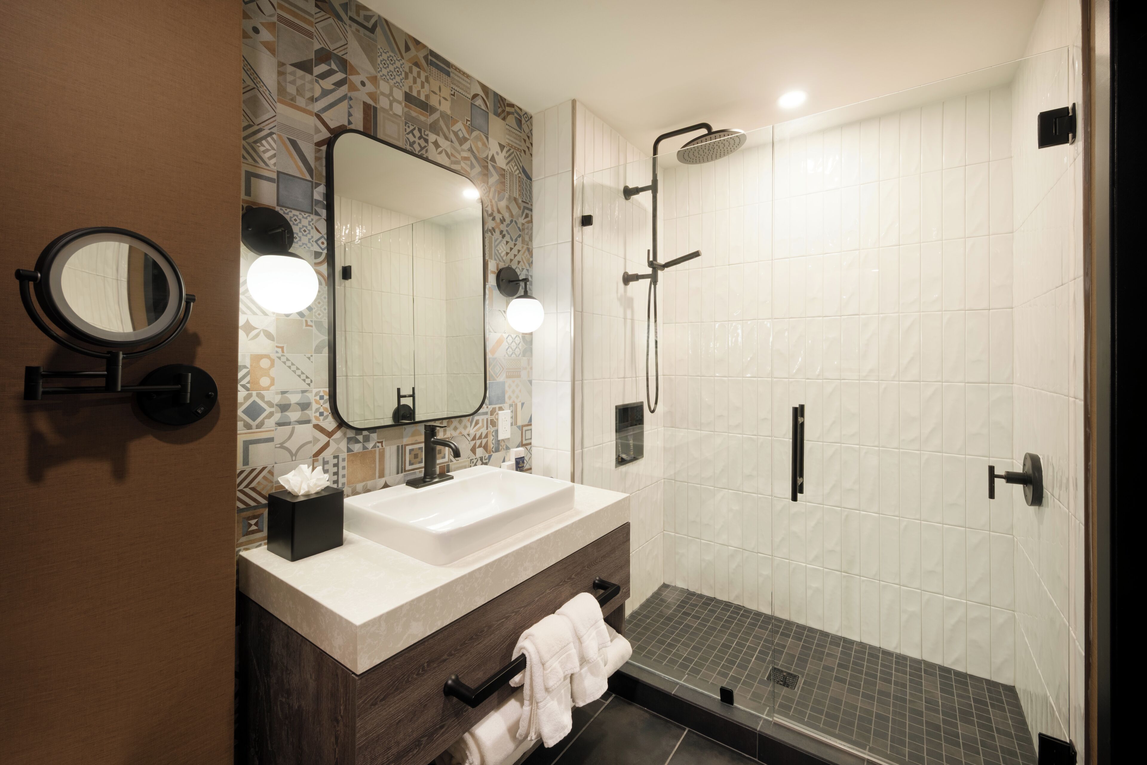 A modern bathroom with a large mirror, a sink, and a shower.
