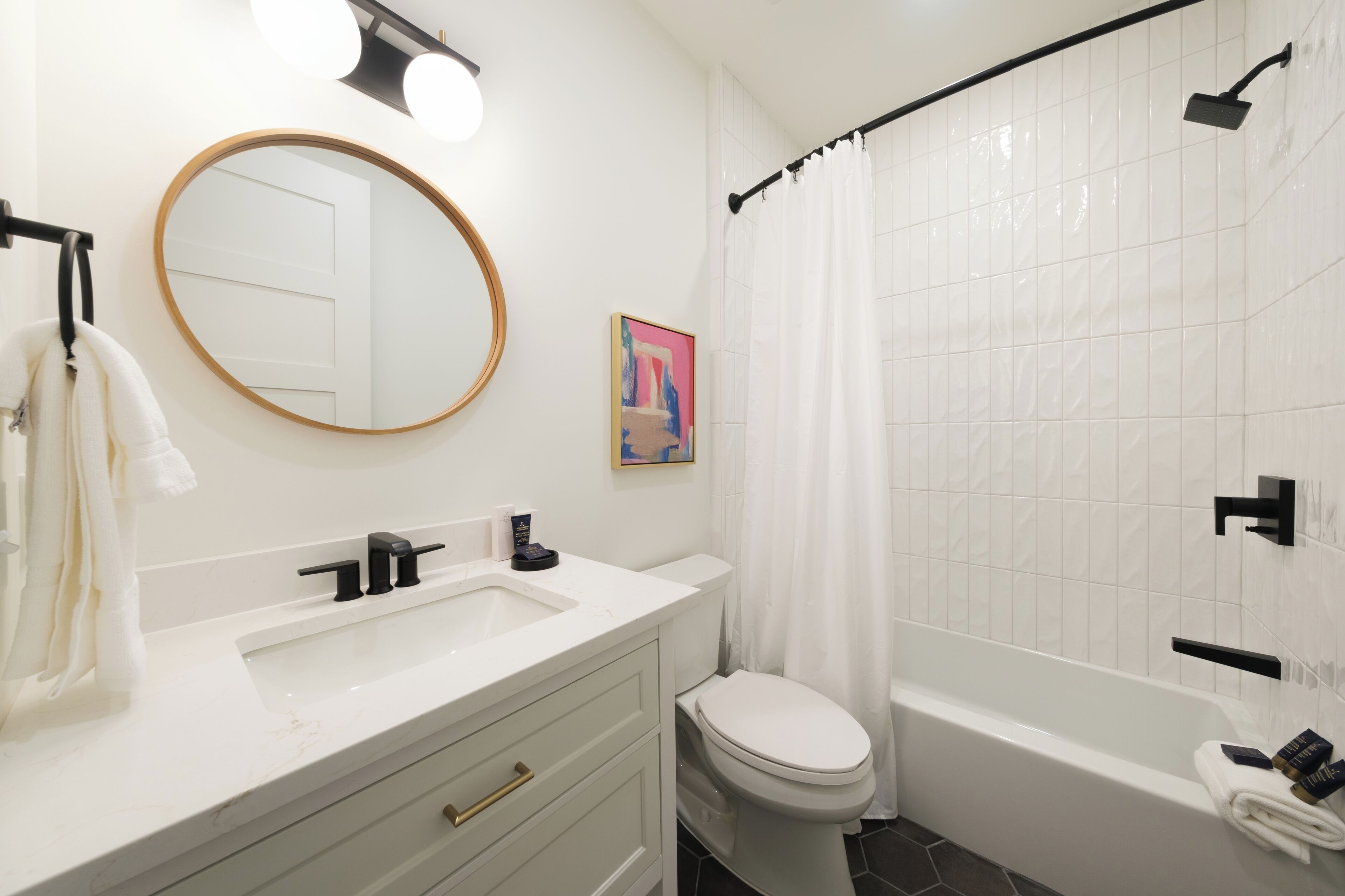 A bathroom with a white sink, a toilet, a bathtub, a shower curtain, and a mirror.