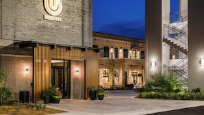 A hotel with a prominent logo, a brick facade, a modern entrance, and a staircase. - OS Hotel  (Ocean Springs)