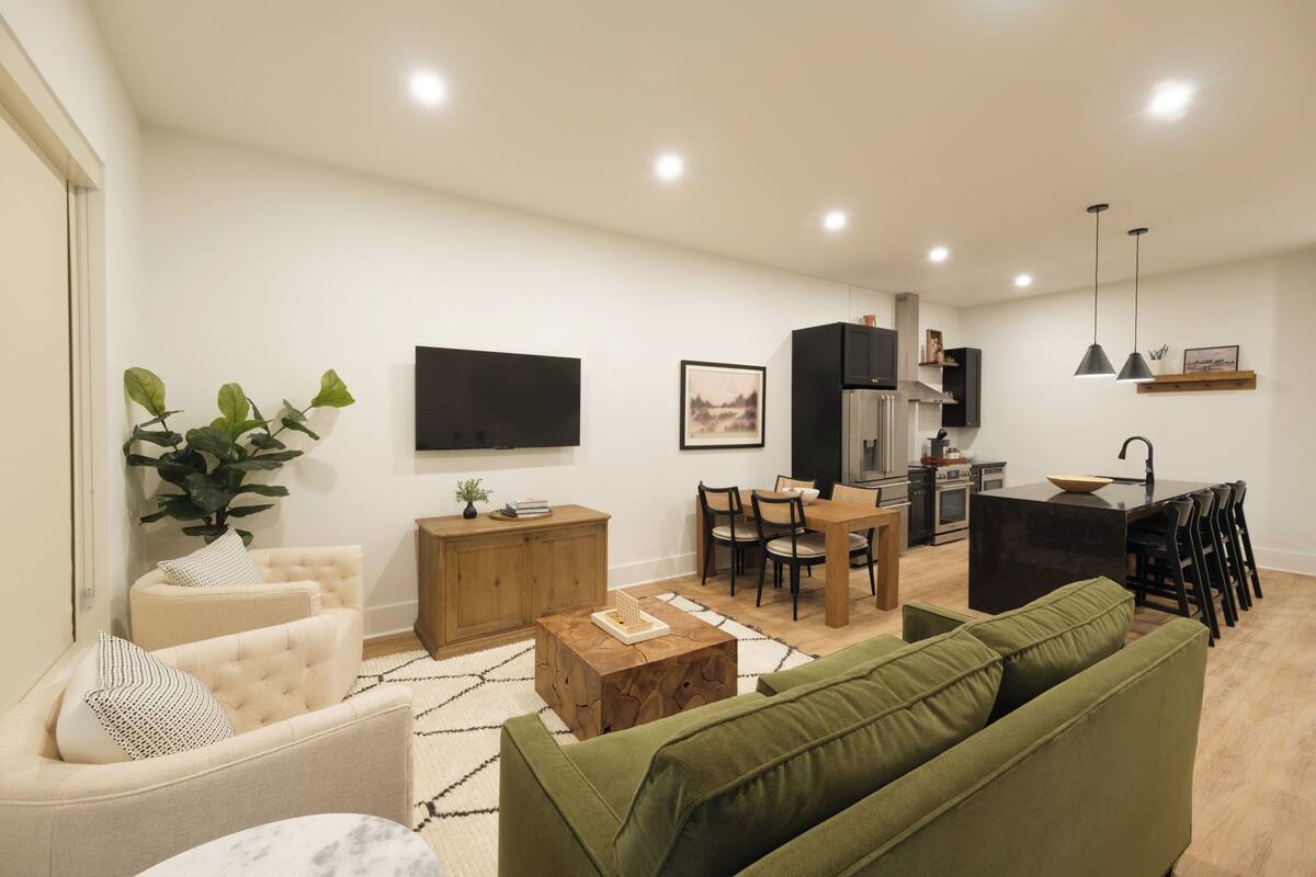 A modern living room with a sofa, a coffee table, and a dining area with chairs and a table.
