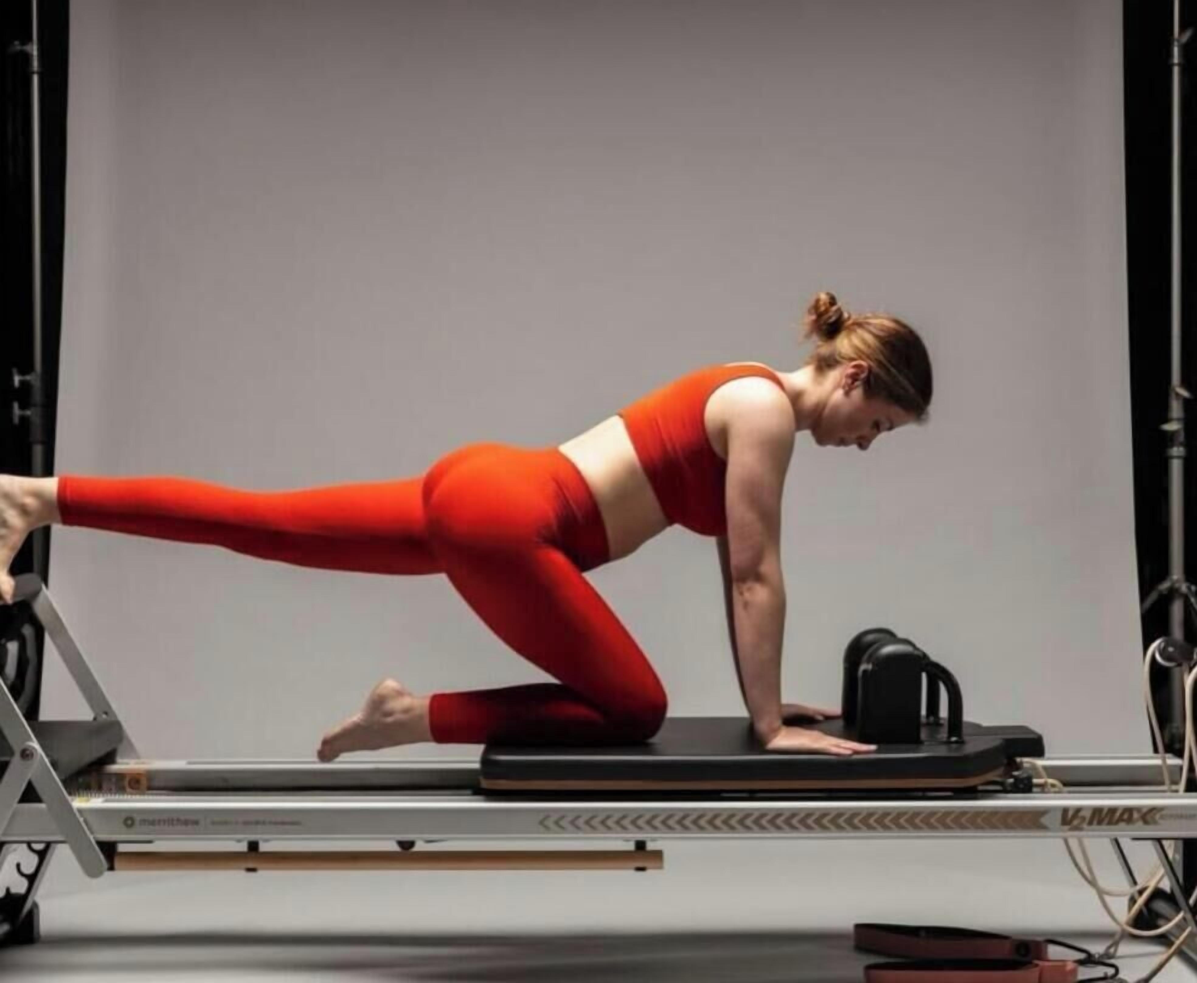 Una persona realizando un ejercicio de Pilates en una máquina reformadora.