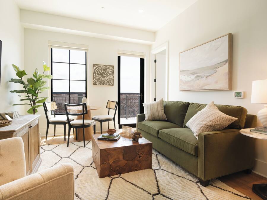 A modern living room with a green sofa, a coffee table, and a dining area with chairs.