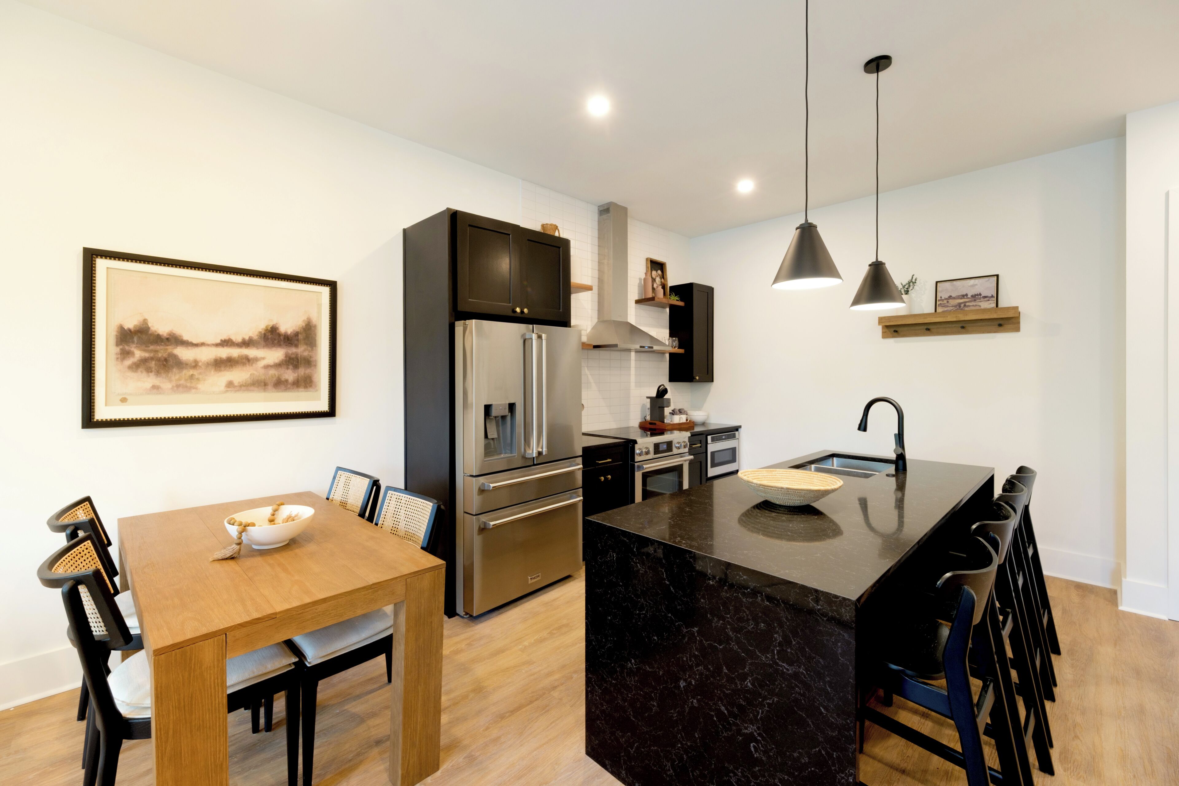 A modern kitchen with a central island, stainless steel appliances, and a dining area with a wooden table and chairs.