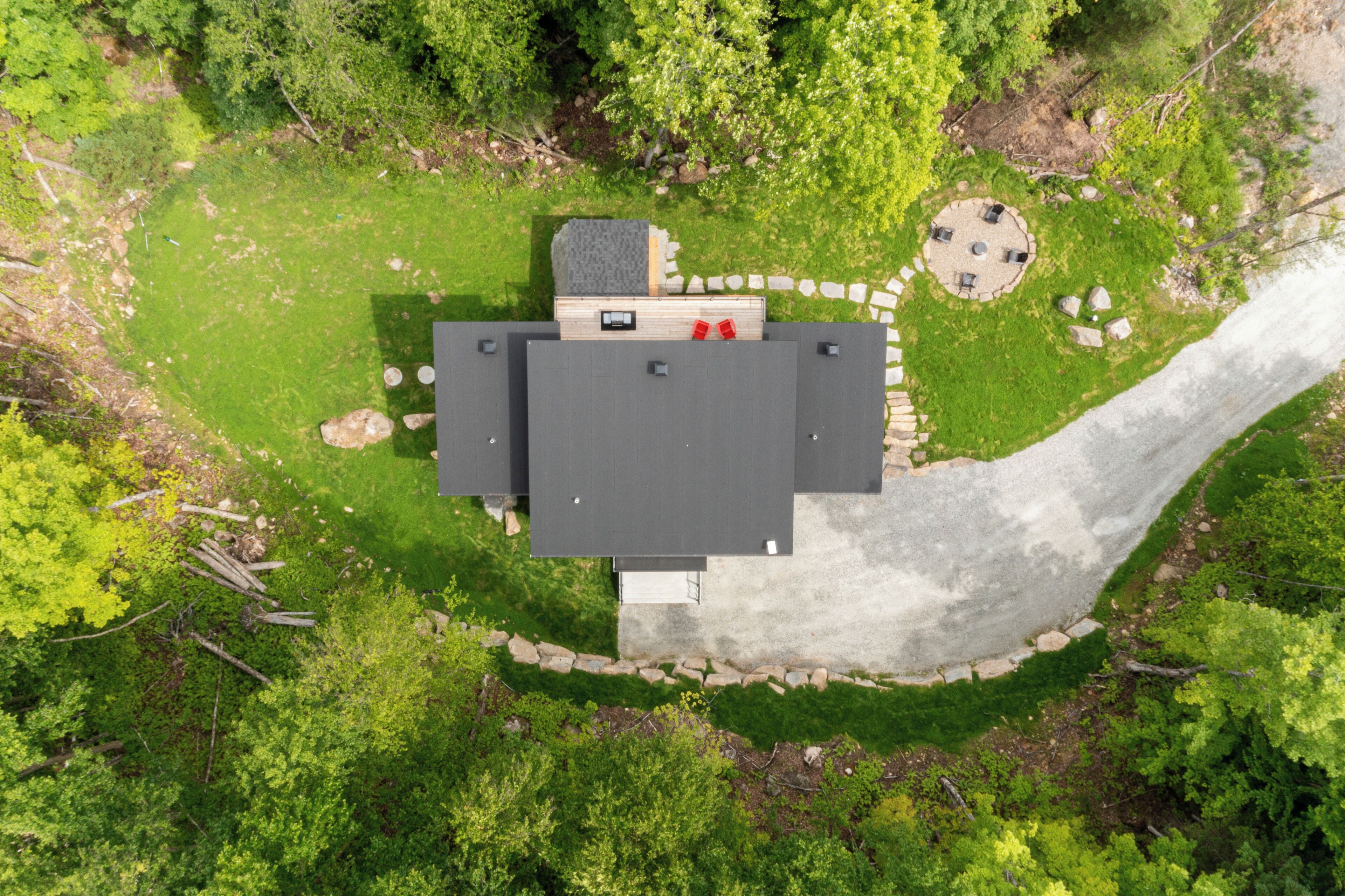 An aerial view of a house with a circular patio, a small deck, and a stone pathway.