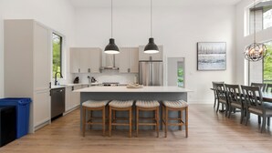 Une cuisine moderne dotée d’un îlot central, de tabourets de bar et de luminaires suspendus.