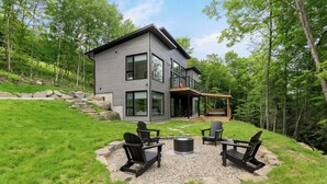 Une maison moderne à deux étages dotée d’une terrasse et d’un espace salon extérieur.
