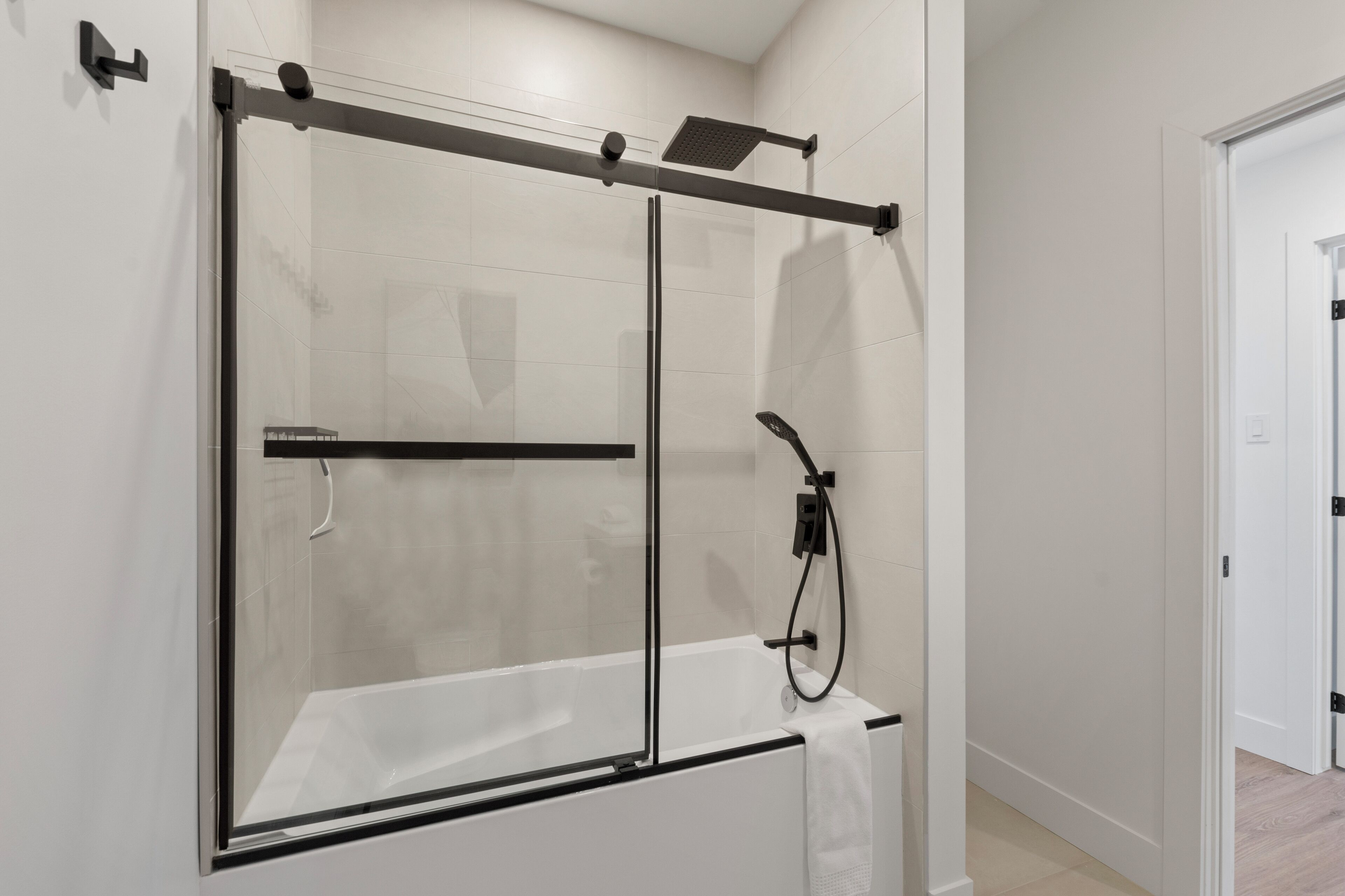 A modern shower enclosure with a glass door and a control panel above the tub.