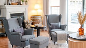 Un salon moderne avec deux fauteuils gris, une table basse ronde et une cheminée.