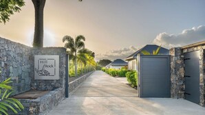 A stone-walled driveway leading to a gated area with a sign reading "Hill Rock."