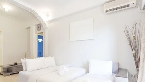 A hotel room with two beds, a clock, a radiator, and a wall-mounted air conditioner. - Spacious and Luxurious Apart Athens Center by MPS (Athina)