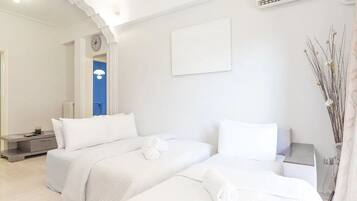 A hotel room with two beds, a clock, a radiator, and a wall-mounted air conditioner.
