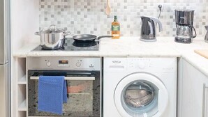 A compact kitchen with a built-in oven, microwave, and a front-loading washing machine. - Spacious and Luxurious Apart Athens Center by MPS (Athina)