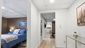 A hotel room with a bed, bedside table, lamp, and a wall-mounted picture. - Spacious Group Home with Arcade (Champaign)