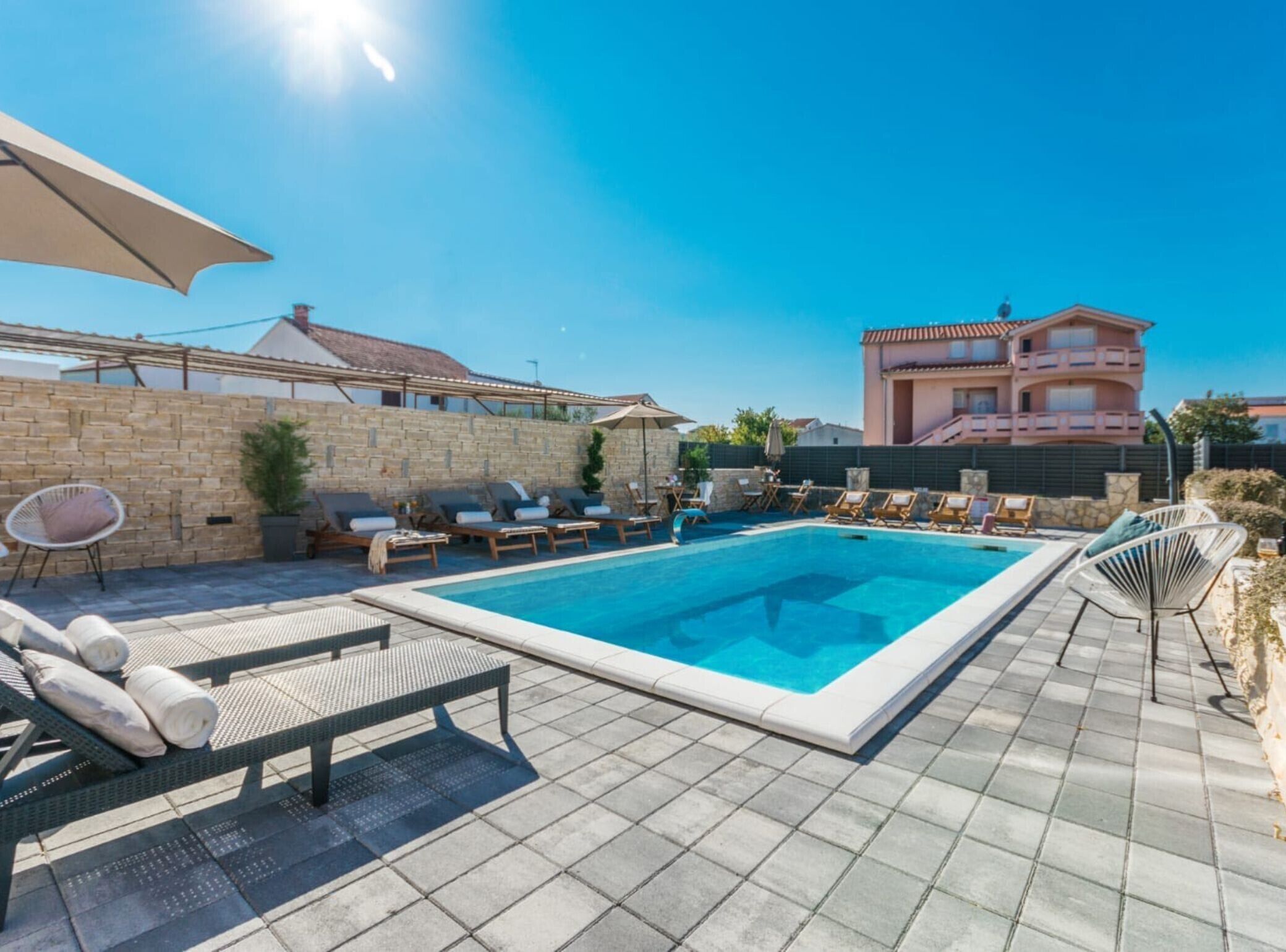 A swimming pool with lounge chairs and a stone wall.