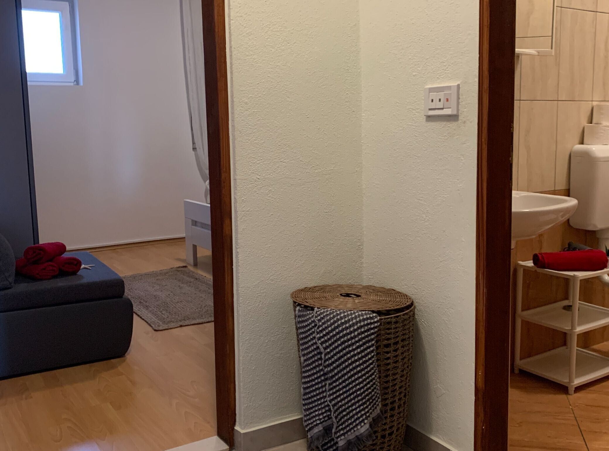 A room with a grey sofa, a small round wicker basket, and a white wall socket.
