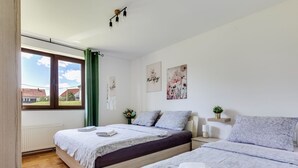 Un dormitorio con dos camas, una ventana con cortinas, un radiador y cuadros en la pared.