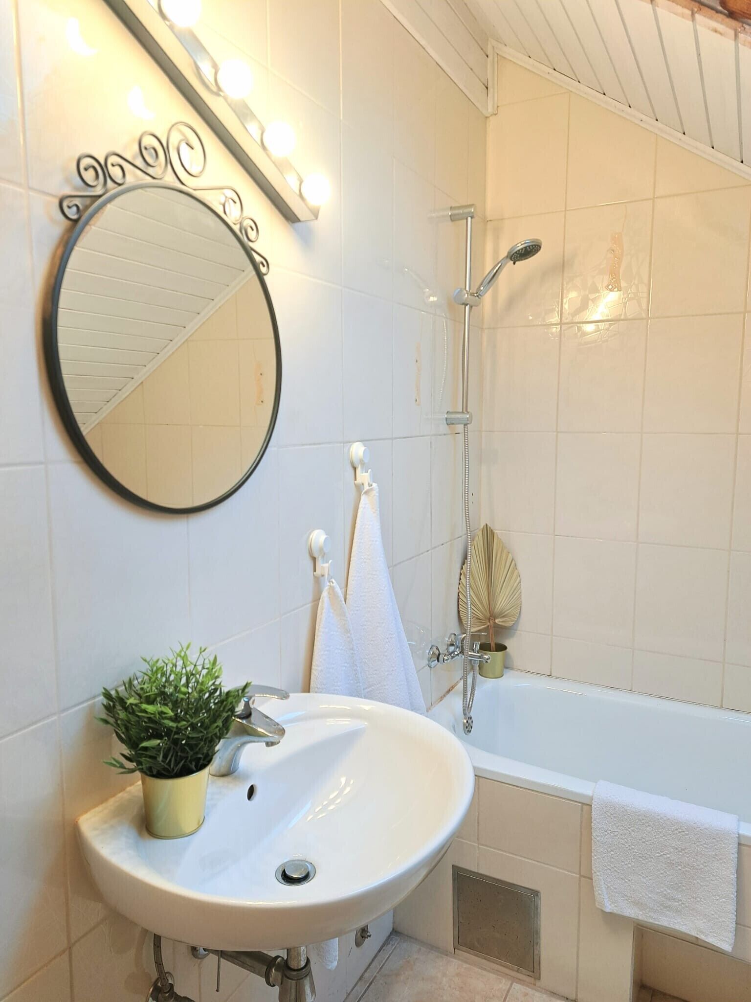 A bathroom with a sink, mirror, and shower.
