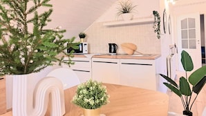 Une cuisine moderne avec des meubles blancs, un plan de travail en bois et diverses plantes.