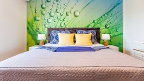 A neatly made bed with a quilted headboard, two bedside lamps, and a green wall mural with water droplets. - Three Bedroom Apartment with Private Pool (Zadar)